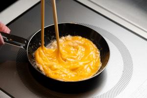 a frying pan filled with orange food with wooden utensils at Shizutetsu Hotel Prezio Tokyo Tamachi in Tokyo