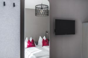 um quarto com uma cama com almofadas vermelhas e uma televisão em Altstadthotel Weisse Taube em Salzburgo