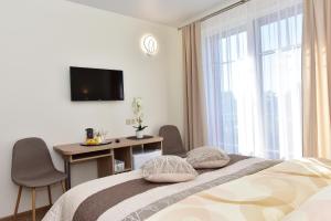 a bedroom with a bed and a desk and a television at Panorama in Trakai