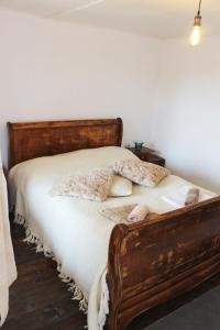 1 dormitorio con cama de madera con sábanas y almohadas blancas en Guest house BULGARKA en Dibich