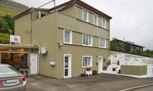 a green house with a car parked in front of it at Romantic Klaksvik apartment in Klaksvík