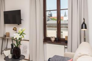 una sala de estar con un jarrón de flores y una ventana en Boho Lofts by LoftAffair, en Cracovia