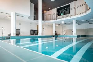 une piscine intérieure revêtue de carrelage bleu et une grande piscine dans l'établissement Hotel Restaurant La Siala, à Falera