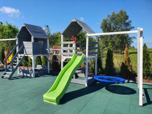 a playground with a green slide and a play structure at Rainbow Resort in Jastrzębia Góra