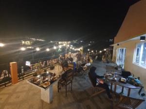 a group of people sitting at tables on a deck at night at Batuque Town Villa 2 in Batu