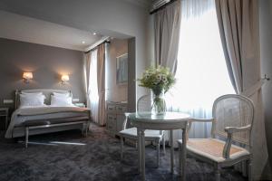 Un dormitorio con una cama y una mesa con un jarrón de flores en Grand Hôtel Bristol en Colmar