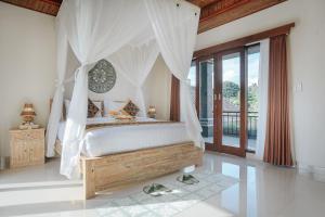 ein Schlafzimmer mit einem Himmelbett mit Sandalen auf dem Boden in der Unterkunft Sitala Suite in Ubud