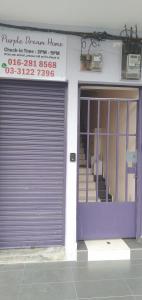 Purple Dream Home في Teluk Panglima Garang: باب المرآب الأرجواني أمام المبنى