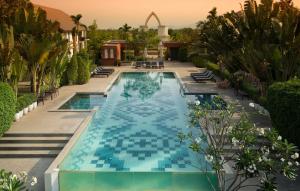 - une piscine avec des carreaux bleus dans un complexe dans l'établissement Sukhothai Treasure Resort & Spa- SHA Plus Certified, à Sukhothaï