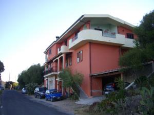 un edificio rojo con coches estacionados frente a él en Appartamento Sofia - Nord Sardegna - Badesi, en Badesi