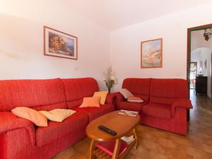 ein Wohnzimmer mit einem roten Sofa und einem Tisch in der Unterkunft Belvilla by OYO Villa Juan in Castelló d'Empúries
