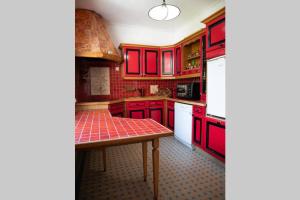 a red kitchen with red cabinets and a table at LA VIGNE in Chailly-en-Bière