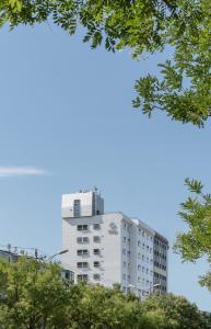 um edifício alto e branco com árvores em frente em Stey 798 Art Zone Hotel em Pequim