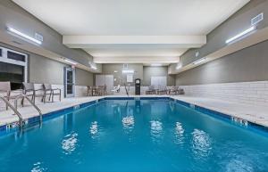- une piscine dans une chambre d'hôtel avec des chaises dans l'établissement Holiday Inn Express & Suites - Coffeyville, an IHG Hotel, à Coffeyville