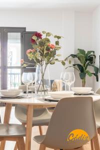 a dining room with a table with chairs and flowers at Corazon del Mar - FREE PARKING by Cadiz Time in Cádiz