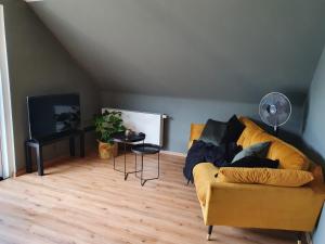 a living room with a yellow couch and a flat screen tv at Moselfeeling co2frei in Cochem
