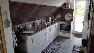 a kitchen with white cabinets and a sink and a microwave at Ferienwohnung Elbkoje in Brunsbüttel