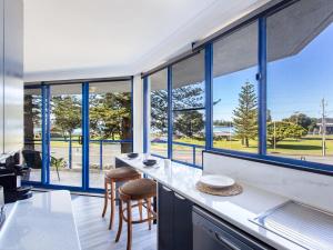 a kitchen with blue windows and a counter with stools at Heritage 202 in Tuncurry