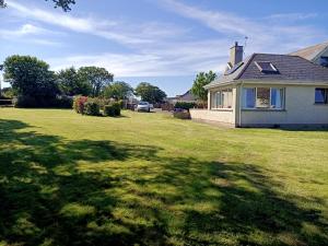 une maison dans une cour avec une grande pelouse verte dans l'établissement Ashlea Bungalow, à Portrush