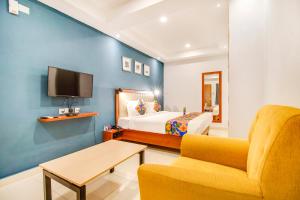 um quarto com uma cama, um sofá e uma televisão em FabHotel The Sun Suites Vinayaka Nagar em Yelahanka