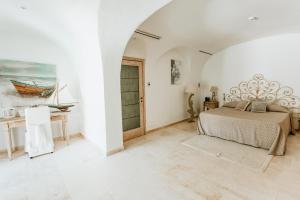a white bedroom with a bed and a table at Hotel Pulicinu in Baja Sardinia