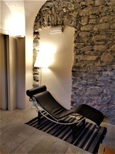 a black chair in a room with a stone wall at Villa Ottocento in Campertogno