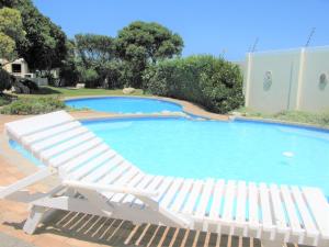 uma espreguiçadeira branca ao lado de uma piscina em Beachfront Cottage - Hermanus Whale View em Hermanus