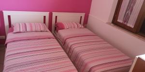 two beds in a room with pink walls at Hawaii Siciliane in Castelluzzo