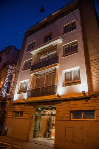 a tall white building with windows on a street at Hotel Serrano in Córdoba