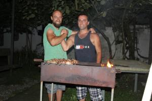 two men standing next to a grill with fire at Lukas's house in Kobuleti