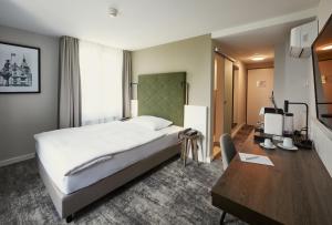 Cette chambre comprend un lit et un bureau. dans l'établissement Hotel Löwen am See, à Zoug