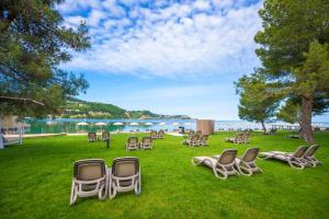 a group of chairs sitting on the grass near the water at Hotel Svoboda - Terme Krka in Strunjan