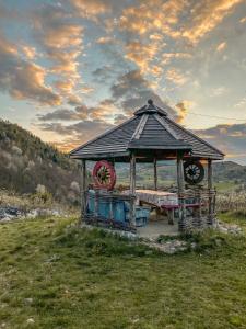 a wooden gazebo with a bench in a field at Etno domacinstvo Saponjic in Nova Varoš