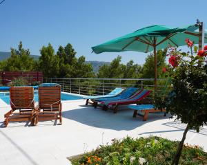 two chairs and an umbrella next to a swimming pool at Apartments Jukic in Klis