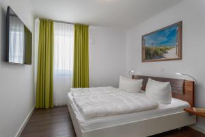 a bedroom with a bed with white sheets and green curtains at Ferienwohnungen Rosengarten in Börgerende-Rethwisch