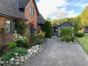 una casa de ladrillo con un jardín de flores en Charmantes Haus mit zwei Ferienwohnungen und großem Garten in Aventoft - Enjoy!, en Aventoft