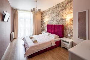 Schlafzimmer mit einem großen Bett mit einem roten Kopfteil in der Unterkunft Romari Гнатюка 3 in Lwiw