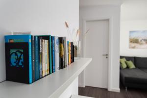 a row of books on a white shelf in a living room at Ferienwohnungen Rosengarten in Börgerende-Rethwisch