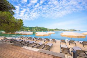 un gruppo di sedie e ombrelloni accanto all'acqua di Holiday Park Vile - Terme Krka a Strunjan