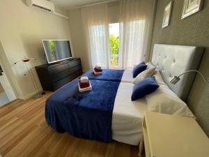 um quarto com uma cama grande com lençóis azuis e uma televisão em Victoria Beach Salou - Exclusive For Families em Salou