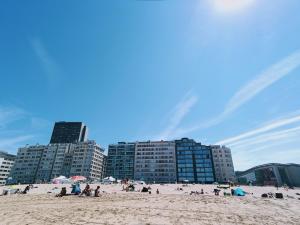 um grupo de pessoas numa praia com edifícios em Geniet van de zee met dit top-appartement Fuji Ostend em Oostende