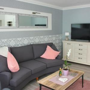 ein Wohnzimmer mit einem schwarzen Sofa und rosa Kissen in der Unterkunft Ferienhaus Godewind in Kühlungsborn