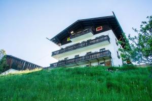 un bâtiment blanc au sommet d'une colline herbeuse dans l'établissement Areithof, à Zell am See