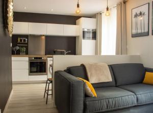 a living room with a couch and a kitchen at Appartement La Madeleine in Lorient