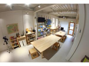 a room with a large wooden table and some shelves at Travelers' house ROOTs in Takaoka