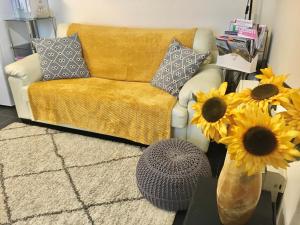 a living room with a couch and a vase of sunflowers at Chapel St Apartments in Caernarfon