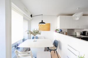 eine weiße Küche mit einem weißen Tisch und Stühlen in der Unterkunft Beautiful Apt With Balcony Parc Montsouris Rer B in Paris