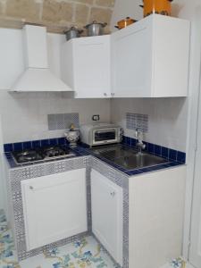 a small kitchen with white cabinets and a microwave at casa vacanze Vico Verona 7 in Oria