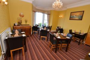 a dining room with tables and chairs and a chandelier at St. Hilary Guest House in Llandudno
