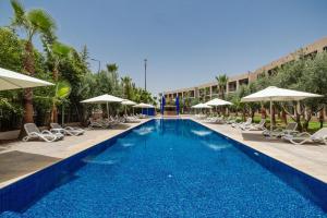 a large swimming pool with chairs and umbrellas at Wazo Hotel in Marrakesh